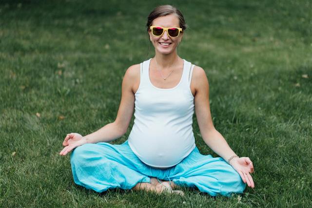 Pregnant yoga woman happy in sunglasses