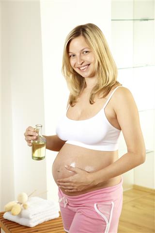 Young pregnant woman with oil for the belly