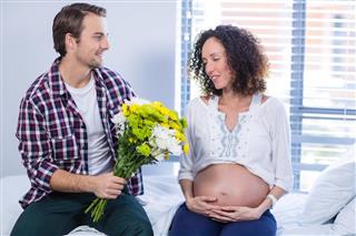 Man offering bunch of flowers to his pregnant woman