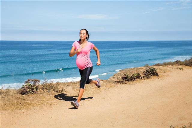 Pregnant woman jogging along the coast