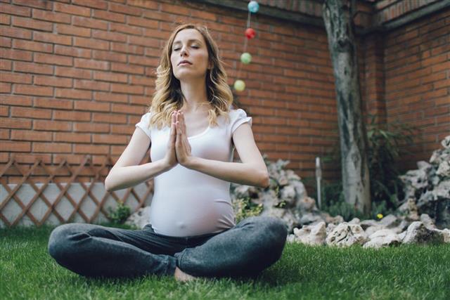 Young Pregnant Woman Practicing Yoga In Her Backyard