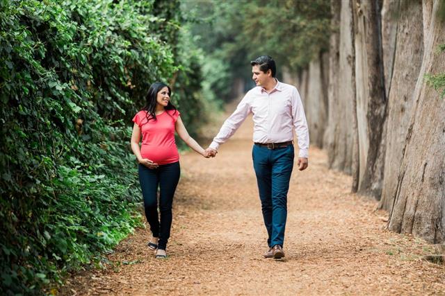 Happy pregnant couple having a walk in the park
