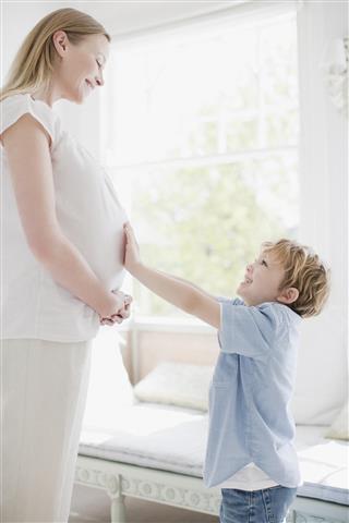 Smiling son touching pregnant mothers stomach