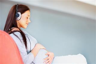 Serene pregnant lady listening to music