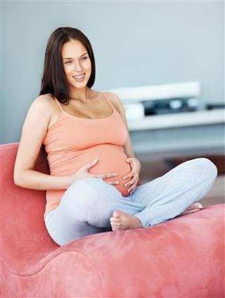 Smiling pregnant lady sitting on a couch