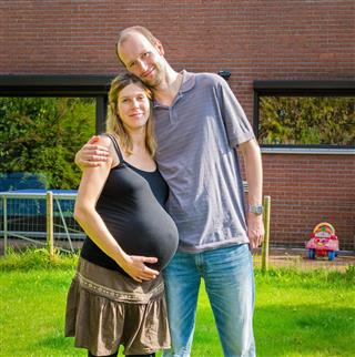 Couple with pregnant wife at garden in front of house