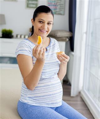 Pregnant woman eating orange
