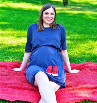 Pregnant woman and red baby shoes