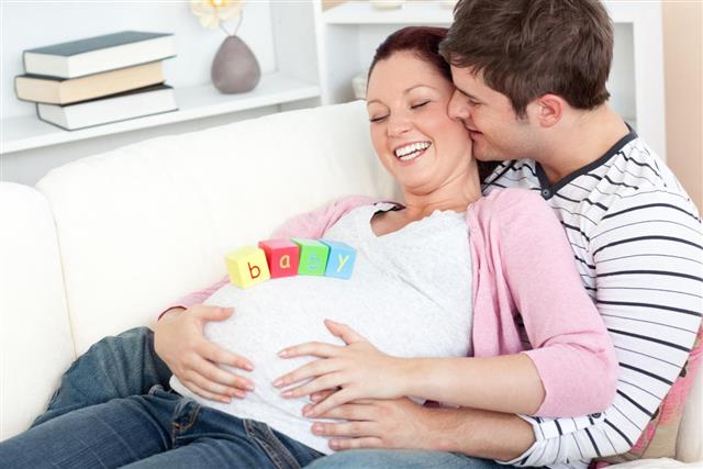 Cheerful pregnant woman with baby cubes on her belly