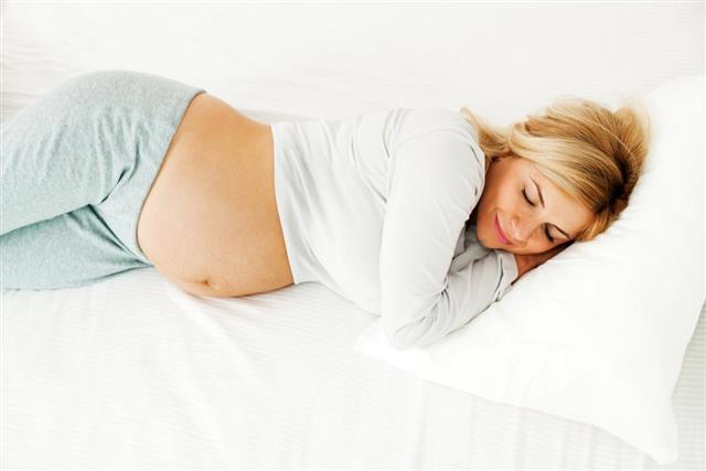Young pregnant woman sleeping in bed