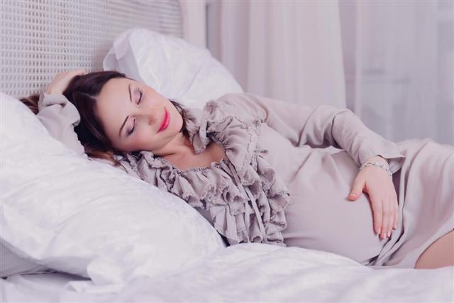 Pregnant woman lying on bed smiling