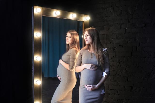 The beautiful pregnant woman in mirror reflection
