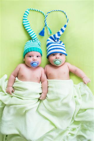 Two twins brothers babies in hats by heart shape