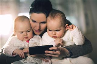 Mother and twins using mobile phone at home