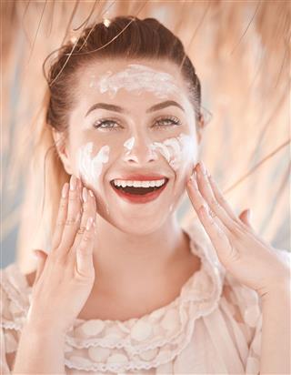 Woman Applying Cream On Face