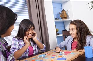 Happy Latin, teenage girls playing board game. Home. Friends, sisters