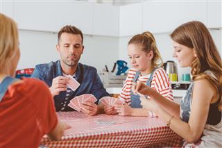 Parents playing cards with their daughters in the kitchen