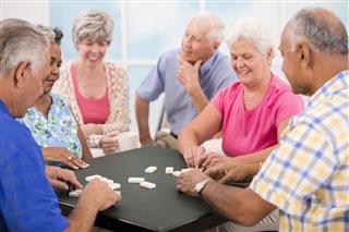 Senior adult friends playing dominoes. Home or community center setting