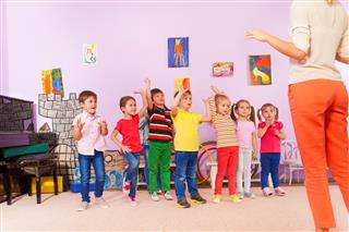 Group of kids repeating exercise after teacher