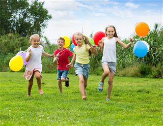 Children running and holding balloons