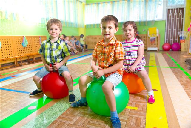 Two boys and a girl playing on bouncy balls in gym