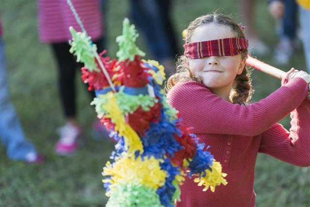 Little girl wearing blindfold hitting a pinata
