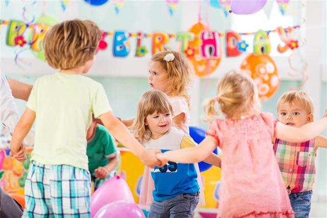 Children playing ring around the rosy at birthday party