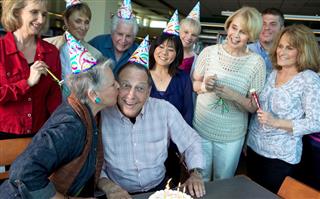 Senior Man Celebrating His Birthday with Friends and a Kiss