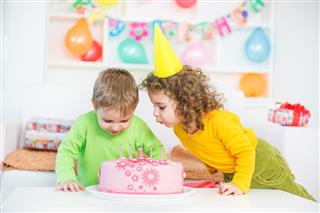 Children Blowing Out Candles on a Birthday Cake