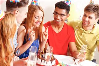 Young people celebrating a birthday sitting at the table