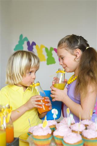 Children drinking orange juice using drinking straw in Easter scene