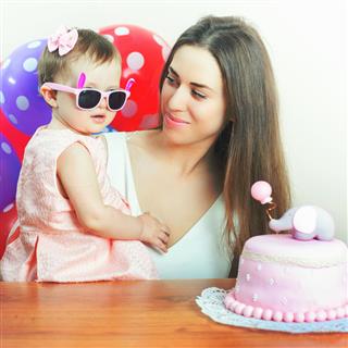 Mother with funny baby celebrating first birthday. Cake
