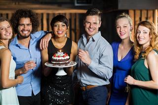 Woman holding birthday cake with her friends