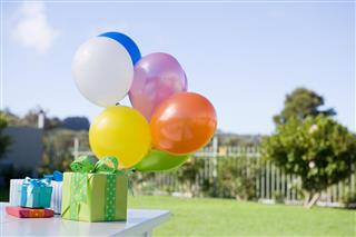 Balloons and birthday presents on table in garden