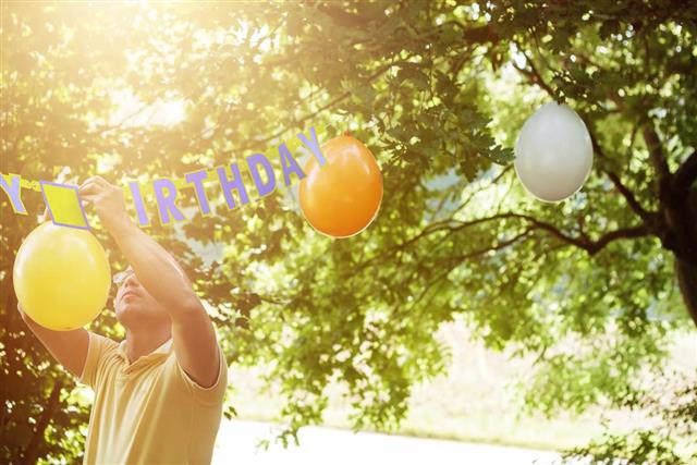 Man hanging up balloons to preparing the birthday party