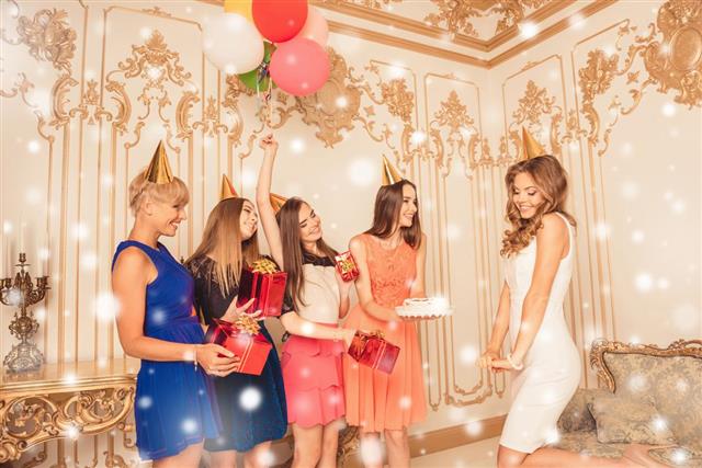 Group of girls with cake and presents congratulating their friend