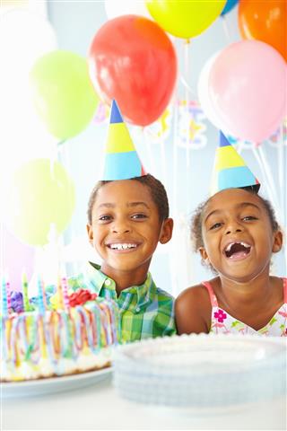 Two children smiling celebrating a birthday with cake