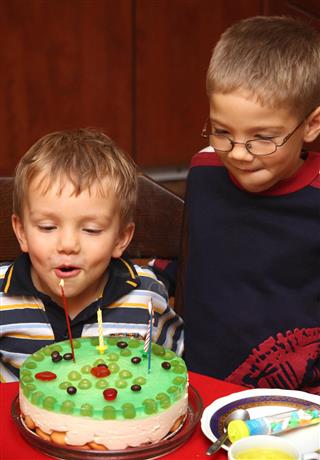 Two boys is blowing candles