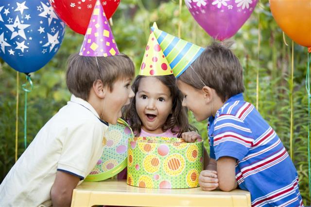 3 little kids at a birthday party all excited about the gift