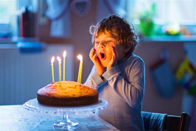 Little kid boy celebrating his birthday with cake and candles