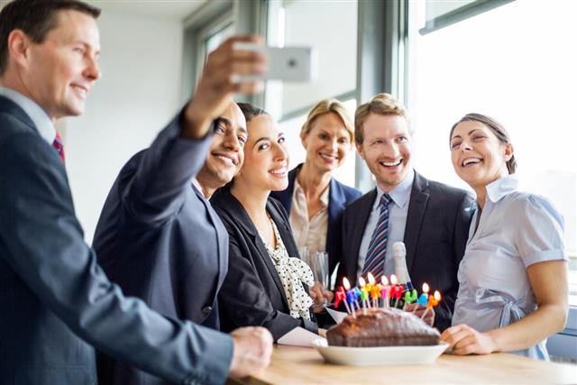 Businessman taking a selfie at birthday party in office