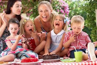 Children And Mothers Eating Cake At Outdoor Tea Party