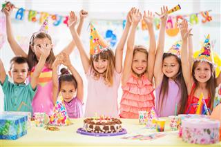 Children celebrating at birthday party with arms raised