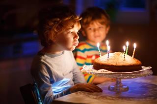 Little kid boy and brother blowing candles on birthday cake