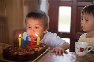 Adorable five year old boy celebrating his birthday and blowing