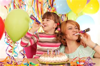 Happy daughter and mother with trumpets and balloons on birthday