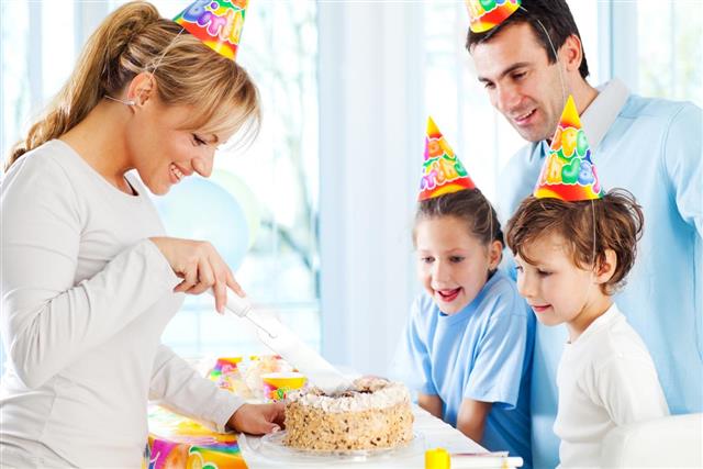 Cheerful boy celebrating birthday with sister and parents