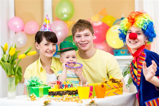 Baby girl celebrating first birthday with parents and clown