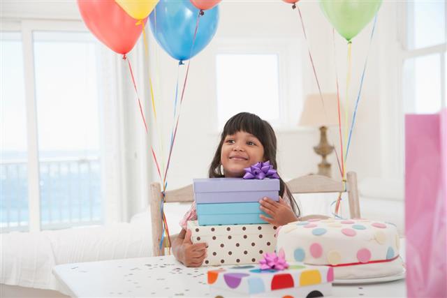 Girl with birthday presents and balloons