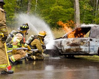Firemen Spraying A Burning Car